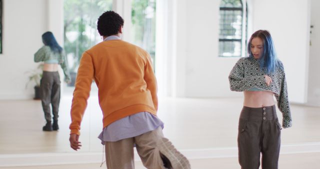 Two young dancers practicing their routine in a bright dance studio with mirrors. This photo can be used in contexts related to dance training, performing arts, teamwork, choreographing routines, and vibrant youth activities. It can also illustrate the interior of a modern dance studio or performance space.