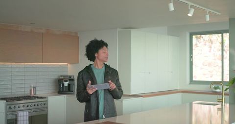Mid-adult african american man inspecting modern kitchen island with tablet