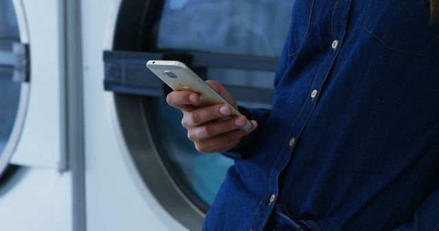 Person using smartphone at laundry mat in casual clothing - Download Free Stock Images Pikwizard.com