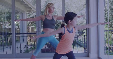 Mother and Daughter Practicing Warrior Pose in Home Yoga Session