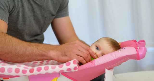 Father Feeding Baby with Bottle, Baby Relaxing in Pink Baby Chair - Download Free Stock Images Pikwizard.com