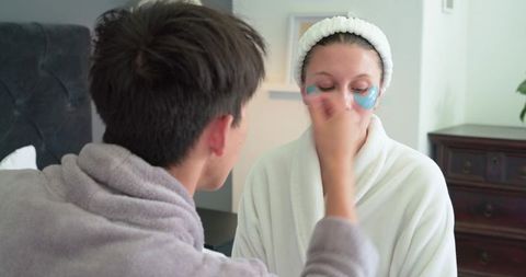 Couple sharing skincare moment: asian man applying moisturizer to african american woman