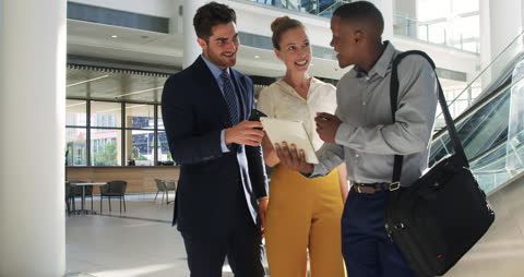 Diverse Business Team Discussing Ideas Using Tablet in Modern Lobby