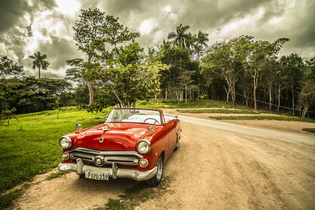 Vintage Red Convertible Parked on Dirt Road Amid Greenery - Download Free Stock Photos Pikwizard.com