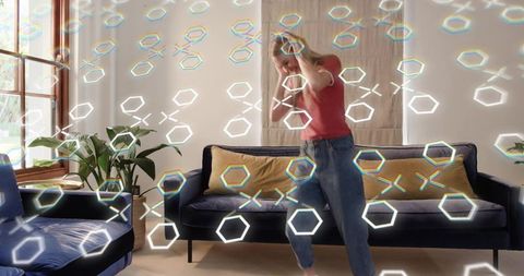 Young woman interacting with holographic augmented reality interface in modern living room