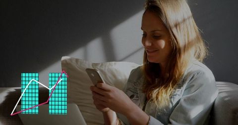 Woman scrolling smartphone on sofa with laptop and turquoise data graph overlay in sunlight
