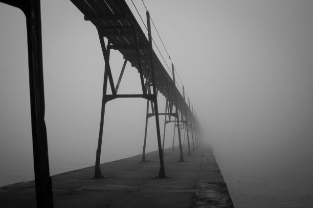 Bridge extending into thick fog, creating a mysterious and eerie atmosphere. Ideal for themes of uncertainty, introspection, and journeying into the unknown. Perfect for dramatic visuals in films, books, articles, or presentations about exploration and the unknown.