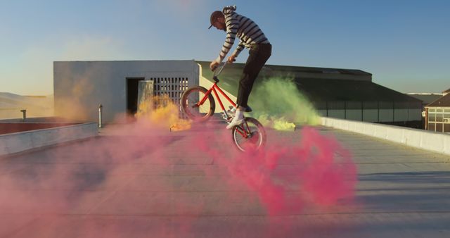 BMX Rider Performing Stunts with Colorful Smoke Bombs on Rooftop - Download Free Stock Images Pikwizard.com