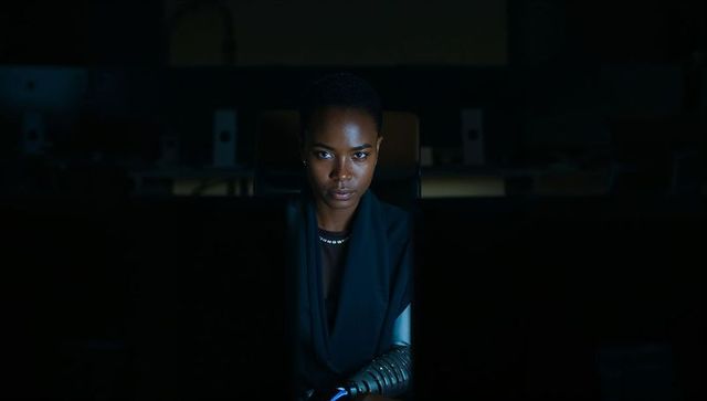 Focused professional working late with wearable forearm device in dark office, tech portrait