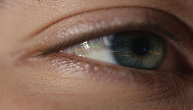 Showing blue-green eye with detailed iris, corneal reflections and skin texture