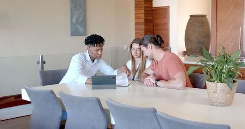 Diverse Group Discussing Project Around Tablet in Modern Office