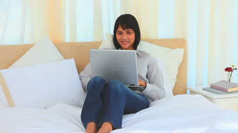 Asian Woman Relaxing on Bed While Using Laptop at Home