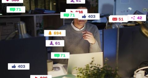 Man working late surrounded by social media notifications and desktop monitors