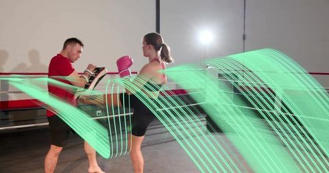 Female boxer delivering kick while trainer holds focus pads with neon motion trails
