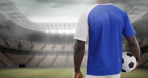Soccer Player Holding Ball on Empty Stadium Field