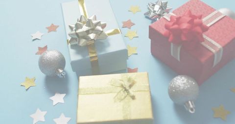 Pastel Holiday Gift Arrangement with Gold, Red and Silver Bows on Soft Blue Background