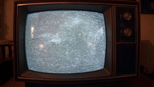 Vintage CRT Television Showing Snowy Static on Wooden Cabinet with Rotary Dials
