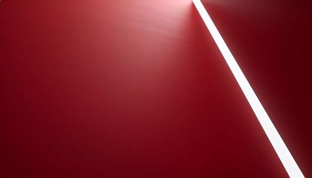 Minimalist diagonal white light slicing scarlet plane with soft halo and ample copy space