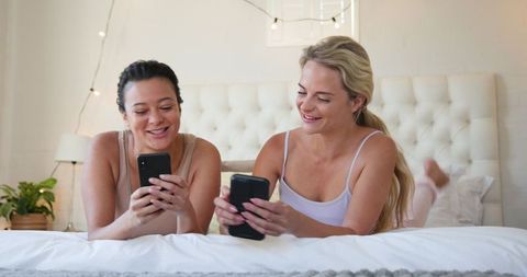 Diverse Friends Enjoying Social Media on Smartphones in Bedroom