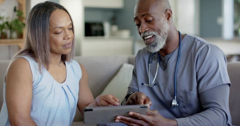 Male healthcare provider explaining tablet results during home telemedicine consultation