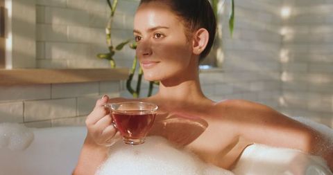 Relaxed Woman in Bubble Bath Enjoying Herbal Tea