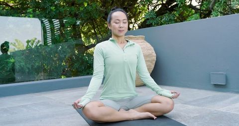 Asian Woman Meditating on Patio for Mindfulness and Tranquility