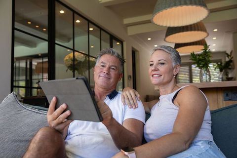 Senior couple relaxing with tablet in modern living room