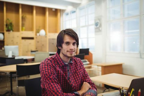 Confident Young Man Seated in Modern Bright Office