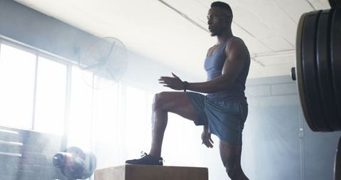 Focused athlete performs box jumps in gym for intense workout