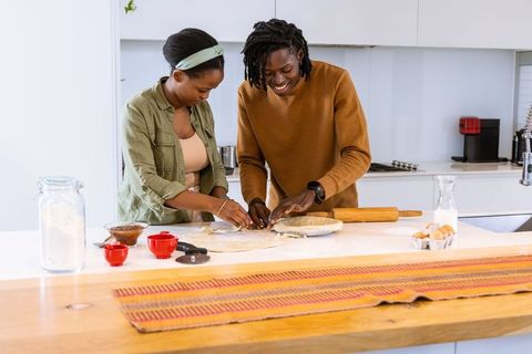 African american couple baking together on bright modern kitchen island preparing pastry