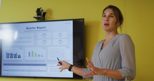 Businesswoman presenting financial report on TV screen in business meeting room. Professional woman sharing quarterly financial insights using charts and graphs to illustrate points. Suitable for corporate, business planning, and professional communication visuals.