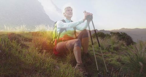 Elderly Hiker Resting on Grassy Hillside at Sunset with Hiking Gear