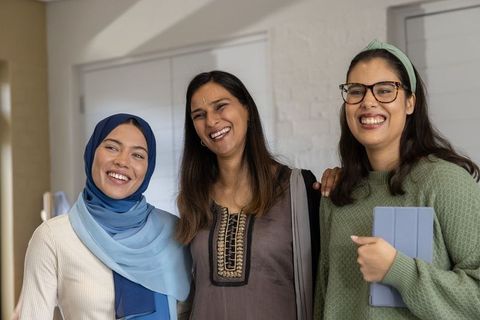 Multicultural women friends smiling and learning together with tablet in bright interior