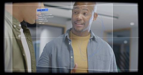 Engineer discussing nanotechnology hologram with colleague, gesturing at augmented reality interface