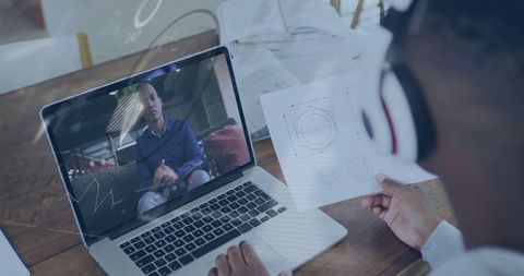 Man Wearing Headphones Holding Schematic During Online Meeting