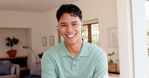 Smiling Young Man in Green Polo Standing Indoors in Bright Living Room - Download Free Stock Images Pikwizard.com