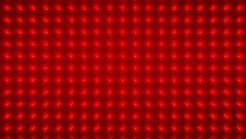 Glowing red led matrix panel forming repeating grid of circular emitters macro texture