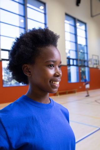 Happy teenage athlete on basketball court in gym