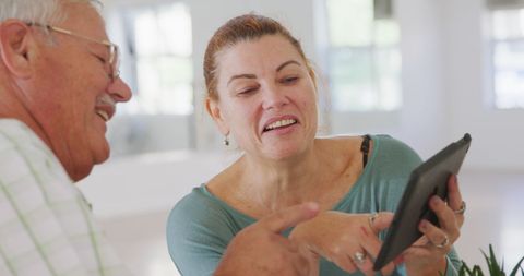 Senior and Mature Friends Enjoy Tablet Conversation in Cafe