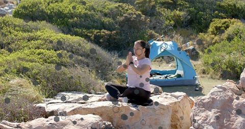 Woman Meditating on Rocks Near Tent in Peaceful Natural Setting