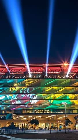 Stadium Facade Projecting Vibrant Mapping and Searchlight Beams in Nighttime Vertical Video