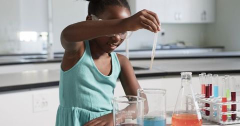Young girl conducting colorful chemistry experiment in school science lab with glassware