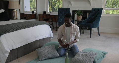 Man practicing mixology in elegant bedroom with cozy decor