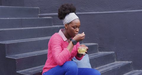 Young Woman Eating Salad Outdoors on Urban Steps