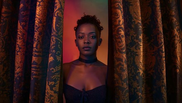 Woman Emerging Through Damask Curtains with Dramatic Gradient Lighting and Moody Portrait