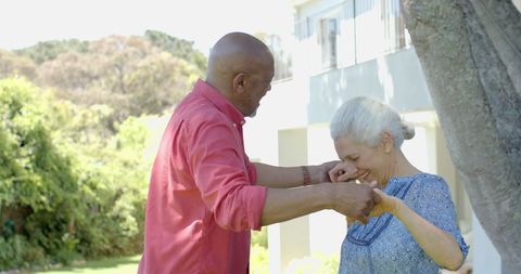 Happy Senior Couple Dancing Outdoors in Sunlit Garden