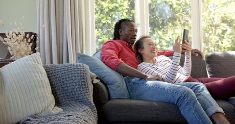 Happy Diverse Couple Relaxing with Tablet on Couch