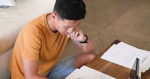 Man Seated on Floor Analyzing Documents with Tablet
