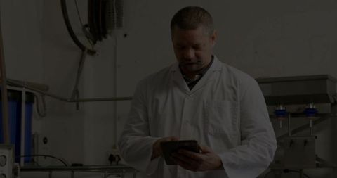 Production Technician Reviewing Tablet Data in Stainless Steel Manufacturing Plant