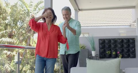 Senior couple celebrating birthday on patio with laughter and cake